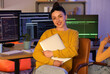 © Pixel-Shot - Female programmer with laptop sitting in office at night