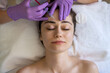 Top view of a woman recieving injection of anti-aging botox filler to forehead from professional cosmetologist in beauty salon. Facial treatment and beauty