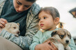 Cute, little girl and her mother holding their puppies outdoors. Kids and pets concept