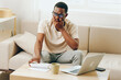 © SHOTPRIME STUDIO - Smiling African American Man Freelancer Working on Laptop in Modern Home Office, Typing Away with a Cyberspace Background
