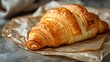   A croissant atop two sheets of wax paper