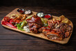 Meat plateau for a large company, pork, ham, chicken, beef kebab, grilled vegetables on dark boards background. Menu for a pub