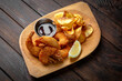 Battered king prawns with barbecue sauce and potato chips on dark boards background. Menu for a pub