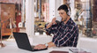 © peopleimages.com - Laptop, workshop and man with headphones, desk and construction office building. Typing, podcast and technology for work in architecture planning, workplace and internet for male entrepreneur