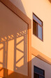 Light and shadow of metal warehouse column on orange concrete wall surface of industrial office building in vertical frame, perspective side view and minimal style