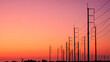 Silhouette two rows of electric poles with cable lines on curve country road against colorful orange sunset sky background after sundown