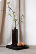 Brown ceramic vase with tree branch, natural brown eggs on table with neutral beige linen curtain and white wall background, aesthetic minimalist Easter holiday decorative still life