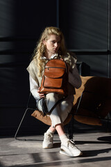 Poster - beautiful curly blond hair woman posing with a leather backpack