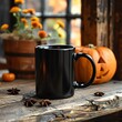 A black coffee mug is sitting on a wooden table in front of a window. There is a pumpkin and some fall foliage on the table. The background is blurry.