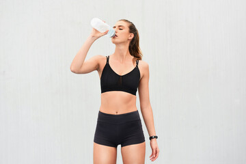 Poster - Woman, athlete and drinking water in studio, thirsty and hydrate after workout on white background. Female person, detox and mineral liquid for recovery after exercise, fitness and mockup space