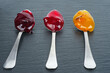 Three colored jam on a spoon on a black background