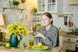 Portrait of a beautiful young girl in the kitchen. Spring flowers in the interior