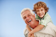 © peopleimages.com - Happy, blue sky and portrait of grandpa and kid for bonding, relationship and relax together outdoors. Family mockup, nature and grandfather with boy on summer holiday, vacation and weekend at park