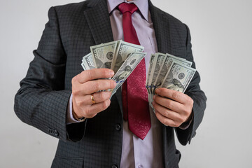 Wall Mural - Man in suit holding and counting cash us dollar isolated on gray