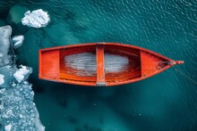 A Vivid Red Rowboat Contrasts Against The Icy Blue Waters, Surrounded By Melting Ice Pieces