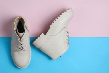 Wall Mural - Women's white leather winter boots on a blue-pink background. Top view