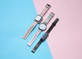 Wall Mural - Modern smart and analog watches and bracelet on a blue-pink background. Top view