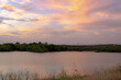 Dramatic sunset clouds reflection along the treelined horizon on Woodlawn Lake San Antonio Texas	