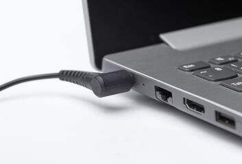 laptop with connected charger cable on white background