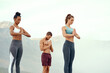 © peopleimages.com - Meditation, training and yoga with friends on beach for mental health, peace or wellness in morning. Exercise, fitness and zen with sporty people outdoor on coast by mountain for balance and mindset