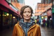 Portrait of a content woman in her 40s wearing a lightweight packable anorak in front of vibrant market street background