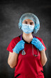 young caucasian female doctor nurse in red uniform, mask and rubber gloves with stethoscope