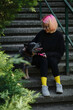 A young attractive woman with pink hair is sitting on the stairs in spring park with her Blue Heeler. Australian cattle dog on a walk with female owner. Family dog outdoor lifestyle concept.
