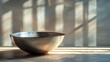 Metal bowl sits on a wooden table near a window with sunlight shining through