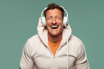 Wall Mural - Portrait of a grinning man in his 40s wearing a zip-up fleece hoodie and headphones over pastel or soft colors background