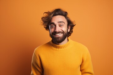 Wall Mural - Portrait of a joyful man in his 30s wearing a cozy sweater while standing against solid color backdrop