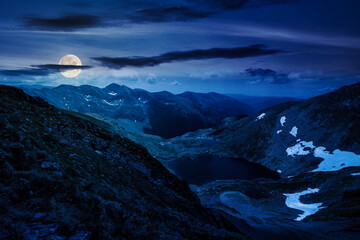 Wall Mural - alpine landscape of fagaras mountains at night. capra lake of romania in summer. spots of snow and g
