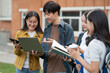 © NINENII - Asian college student focusing on laptop work or reading while other classmates in the background, outdoor portrait on campus campus.