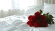 白い寝具のダブルベッドの上の真っ赤な薔薇の花束