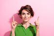 © deagreez - Photo of cheerful positive young woman dressed green shirt pointing two fingers up empty space isolated pink color background