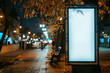 © Emanuel - An unbranded white vertical banner billboard stands on a sidewalk at night, ready for advertising content