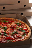 Fototapeta  - Large Pizza in open carton box on kitchen table closeup view