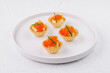 Elegant tartlets with salmon caviar on white plate