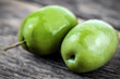 Two green olives on wooden background
