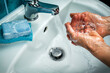 Washing of hands with soap over sink in bathroom.