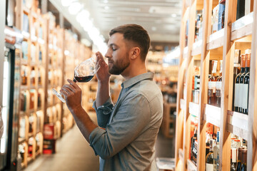 Wall Mural - Drink tasting. Man is choosing wine in the store