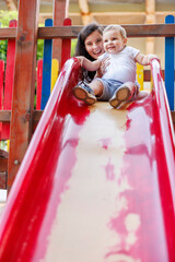 Wall Mural - Mother and child playing on a slide in the park