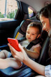 Mother playing cartoons to baby using smart phone while riding in car