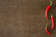 Fresh red hot chili peppers on dark brown wooden table background. Closeup. Empty place for text. Top view.