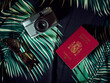 A Spanish passport, a camera and sunglasses over a Hawaiian bedcover