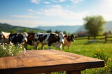 Fototapeta Tulipany - Empty wooden table top and blurred rural background of cows on green field and meadow with grass. Space for design your dairy organic product.