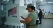 © Framestock - Female American army soldier votes in booth in polling station office. National Elections Day in the United States. Political races of US presidential candidates. Concept of civic duty. Dolly shot.