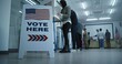 © Framestock - Vote here sign on the floor. Multi ethnic American citizens vote in booths in polling station office. National Election Day in United States. Political races of US presidential candidates. Civic duty.