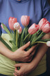 a woman holding a bouquet of pink tulips