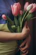 a woman holding a bouquet of pink tulips