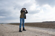 © hiv360 - female ornithologist birdman or explorer watches birds with binoculars against a background of a stormy sky